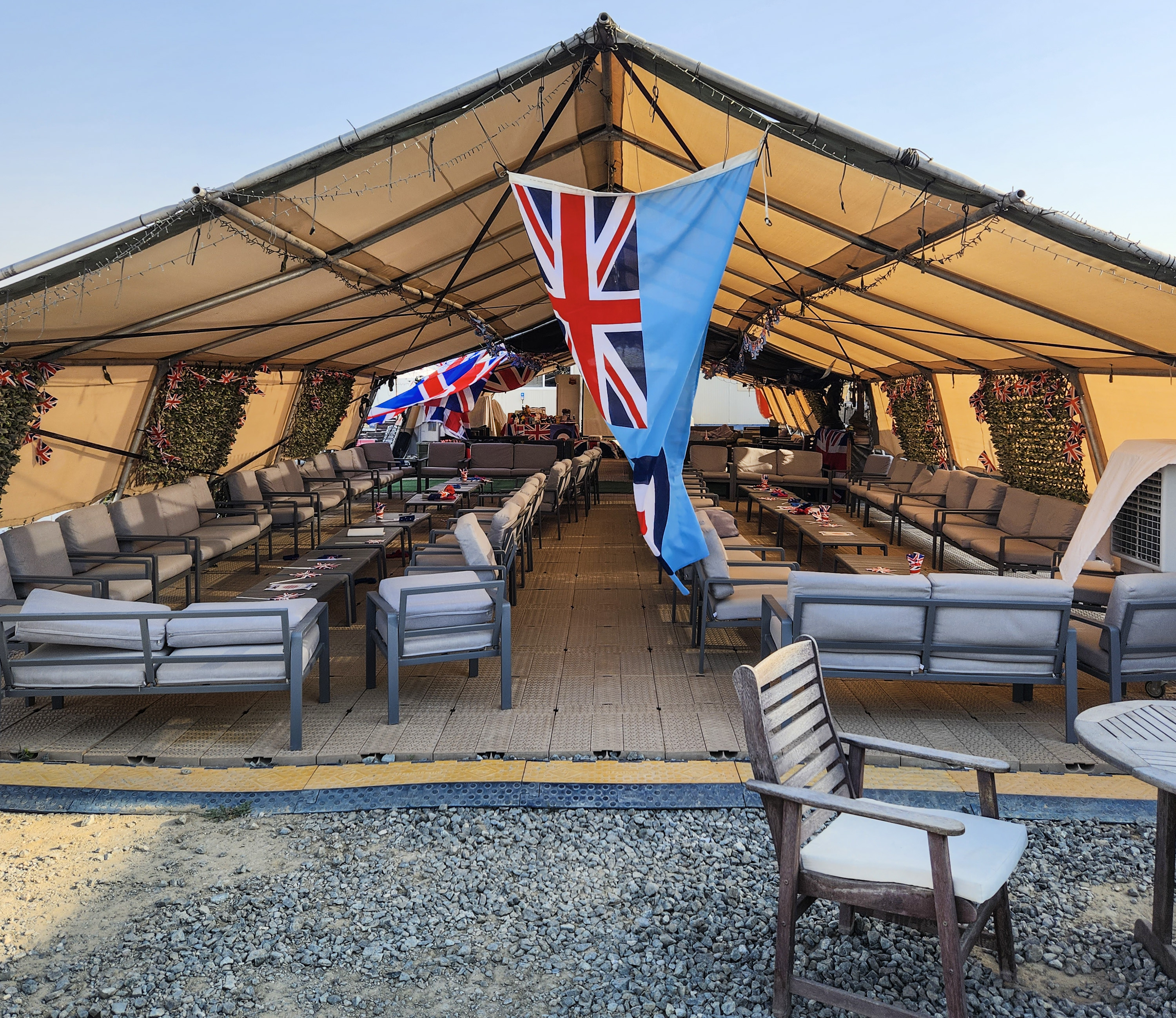 Image shows temporary tent with chairs and flag.